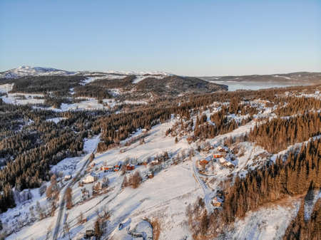 A high angle view of a village covered in the snow surrounded by forests and a lakeの写真素材