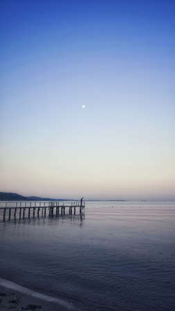 A vertical shot of a pier leading to a breathtaking view of the oceanの写真素材