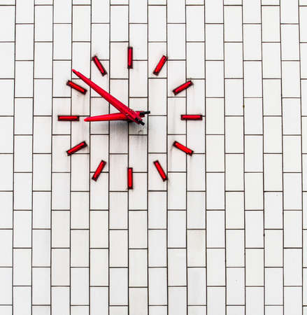 A red clock on a white brick wallの写真素材