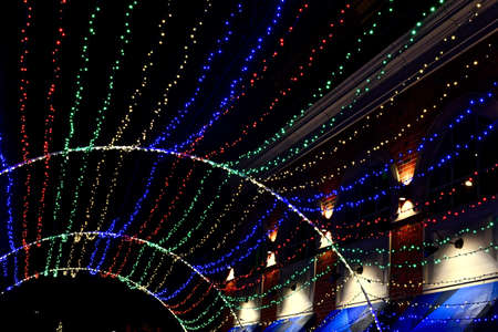 A Christmas decoration with colorful lights near a building during the nightの写真素材