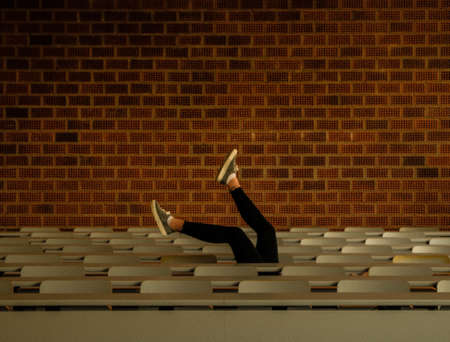 The legs of a person from the below of desks in front of a cobblestone wallの写真素材