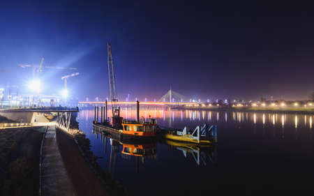 View on two ships reflected in the Sava river, distant Ada bridge and Gazelle bridge at nightの写真素材