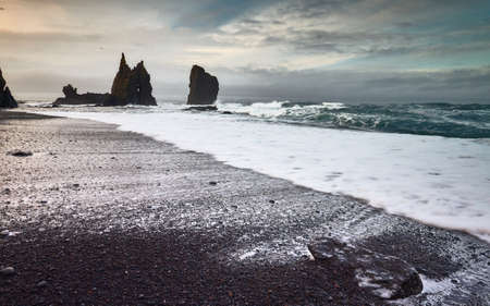 A beautiful shot of sea waves coming up on the shore under a cloudy sky