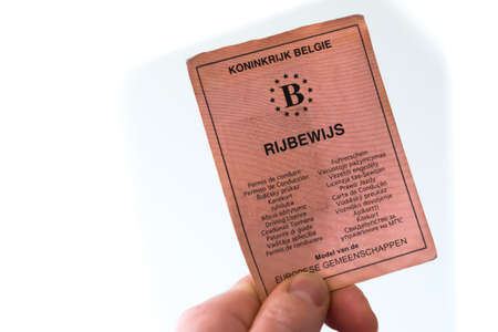 ANTWERP, BELGIUM - Oct 02, 2019: Antwerp, Belgium, October 2019, Illustrative Editorial: Hand holding old-fashioned red paper driver's license from Belgium. Isolatedのeditorial素材