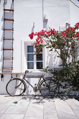 OÃ­A, GREECE - Jul 19, 2017: Vertical shot of an old bike under a window in front of a white wall in OÃ­a on Santorini Island - Greeceのeditorial素材
