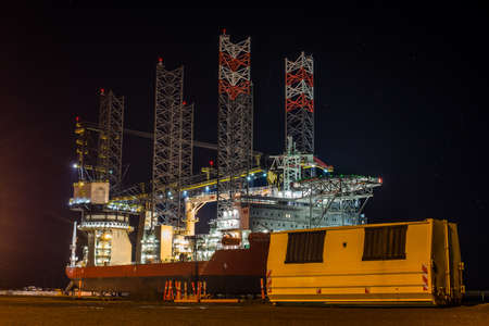 A shot of an anchor handling tug supply vessel parked on the shore with  the dark night sky in the...