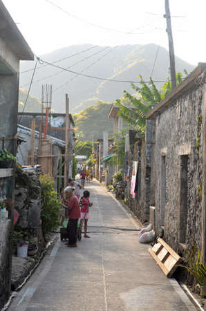 An alley with stone houses and children playing in the road with greenery and hills on the backgroundのeditorial素材