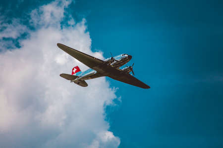 A horizontal low angle shot of a silver airplane under the beautiful cloudy skyのeditorial素材
