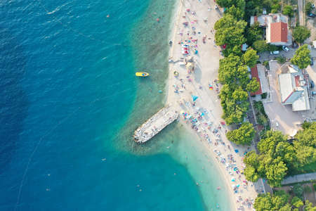An aerial shot of a beat on the water near the shore with building st daytime in Makarska, Croatiaのeditorial素材