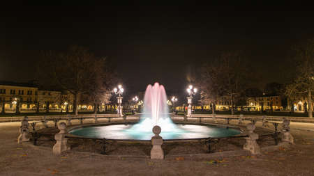 A horizontal shot of a beautiful fountain surrounded by street lights and buildings at night in Padova, Italyのeditorial素材