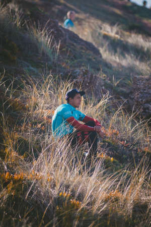NAZARÃ©, PORTUGAL - Aug 06, 2019: A vertical shot of a male surfer relaxing at the grassy shore of the oceanのeditorial素材