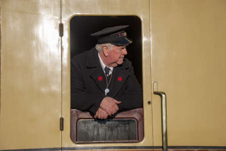 DIDCOT, UNITED KINGDOM - Feb 17, 2008: Guard leaning out of a steam train carriage windowのeditorial素材