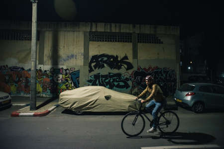 TEL AVIV, ISRAEL - Dec 12, 2019: A cyclist passing by a wall graffiti on a street in Tel-Aviv, Israelのeditorial素材