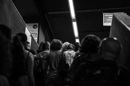 A greyscale shot of a group of people walking in a metro stationのeditorial素材