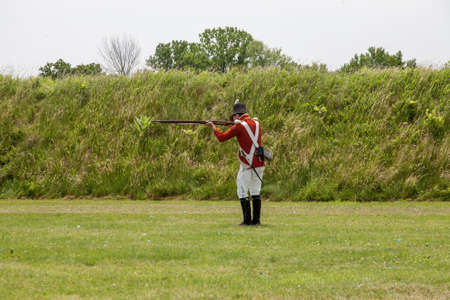 NIAGARA ON THE LAKE, CANADA - Jun 20, 2019: Actor dressed like an 18th century soldier is preparing to fire a musket.  Location is Fort George a historic military structure at Niagaraのeditorial素材