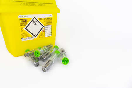 LEEDS, UNITED KINGDOM - Jan 27, 2019: A bright yellow sharps bin with used Tocilizumab injection bottom of the frame.のeditorial素材