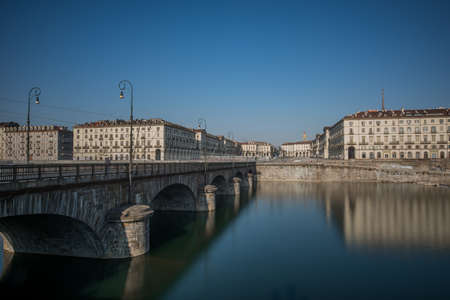 A horizontal shot of a concrete bridge with arches over the beautiful lake near apartment buildings in Turin, Italyのeditorial素材