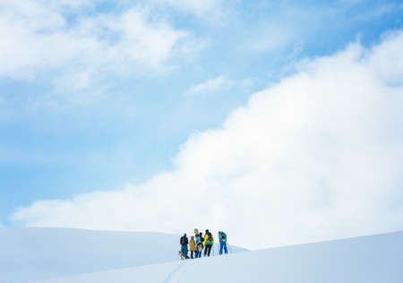 A group of people hiking in the mountains covered in snow under the beautiful blue skyのeditorial素材
