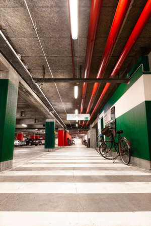 A vertical shot of an interior of a  parking lot with green  walls and red pipes on ceilingsのeditorial素材