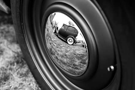 PORTLAND, UNITED STATES - Jun 15, 2019: A grey scale shot of the reflection of a vintage car in another car's wheelのeditorial素材