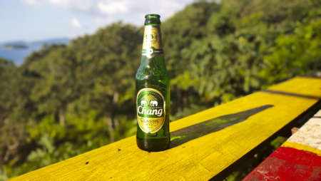 PHUKET, THAILAND - Nov 10, 2019: bottle of chang beer and the shadow of the bottle with the jungle and sea in the backgroundのeditorial素材