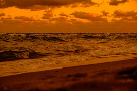 A beautiful scenery of the sunset reflecting on the sea under the golden cloudsの写真素材