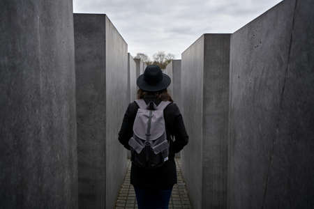A female in black outfit and a backpack walking in the holocaust memorial in Berlinのeditorial素材