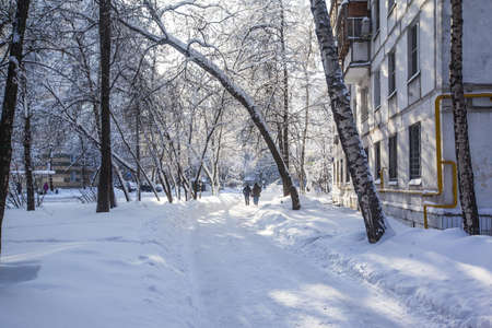 A horizontal shot of a snowy road in a park near an apartment building in Moscow, Russiaのeditorial素材