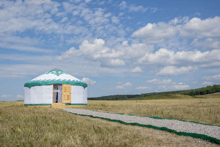 A white yurt (the house of nomadic people, Bashkiria) stands in the steppe with an open door against a blue summer skyのeditorial素材