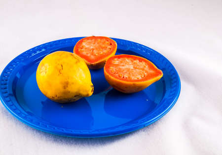 An overhead shot of a yellow ripe passion fruit placed in a blue plate with a white color in the...