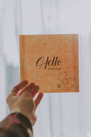 A closeup shot of a small poster held in someone's hands that reads Hello Sunshine
