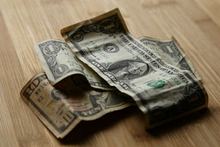A selective focus shot of dollar bills on top of each other on a wooden surface