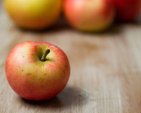 A closeup shot of a red apple on a wooden surface with a blurred background