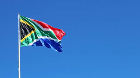 A low angle shot of the South African flag in the wind under the clear blue sky