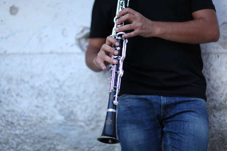 A shallow focus shot of a person playing clarinet in front of a white wallの写真素材