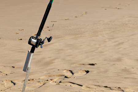 A closeup shot of a fishing pole in a sandy surfaceの写真素材