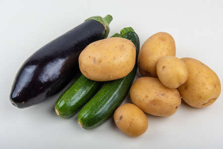 a high angle shot of eggplant zucchini and potatoes with white background