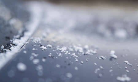 A closeup, shallow focus shot of snow on a car hood