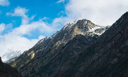 A low angle shot of high rocky mountains under a cloudy
