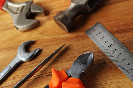 A high angle shot of a ruler, a hammer, a screwdriver and other tools on a wooden surface