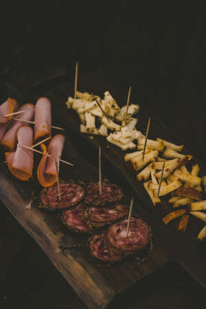 A vertical shot of sliced cheese and baloney on a wooden board