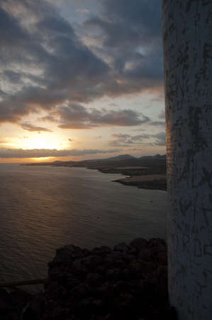 A landscape of a sea surrounded by mountains under a cloudy sky during a beautiful sunset