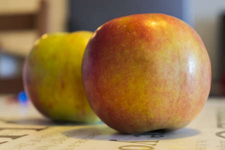 A closeup shot of two yellowish red round apples on a table