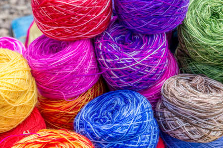 A high angle shot of colorful yarn balls piled up on each other
