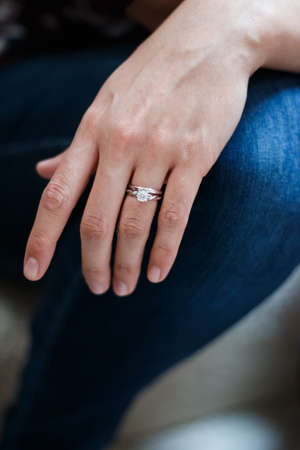 A vertical shot of a person's hand with an engagement ring