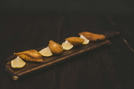 A high angle shot of fried food near lemon sliced on a wooden surfaceの写真素材