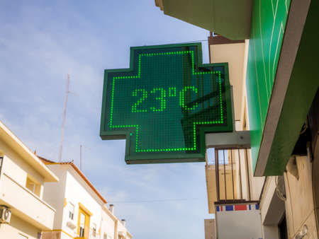 A low angle shot of the sign of pharmacy with a thermometer displaying 23 degrees Celsiusの写真素材