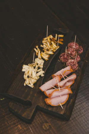 A vertical shot of sliced cheese and baloney on a wooden boardの写真素材