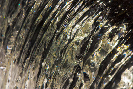 A closeup shot of the crystal water pouring from up to down direction