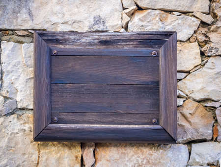 An empty wooden sign with copy space on a concrete wallの写真素材